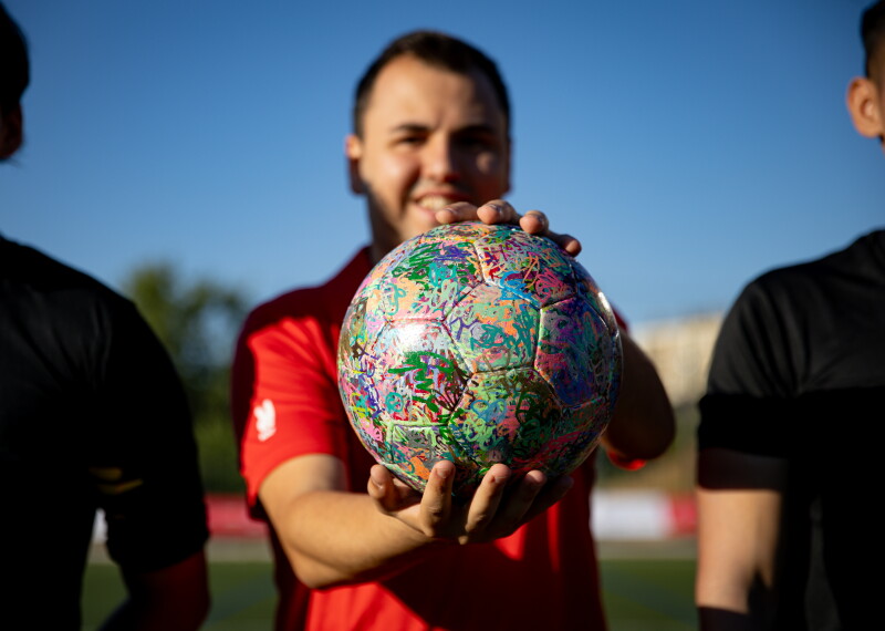 Young adult athlete holds and shows off a football. 