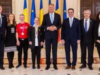 Group of people standing on either side of Romanian President Klaus Iohannis. 