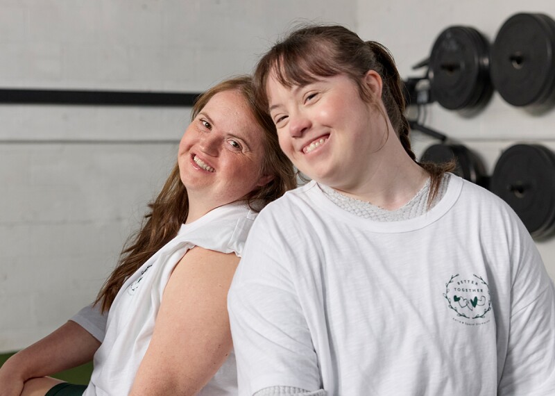 Two young women back to back smiling and posing for a photo. 