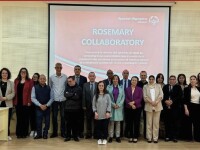 A group of individuals sit in a conference room with a projector in the middle showing a PowerPoint titled “Rosemary Collaboratory.”