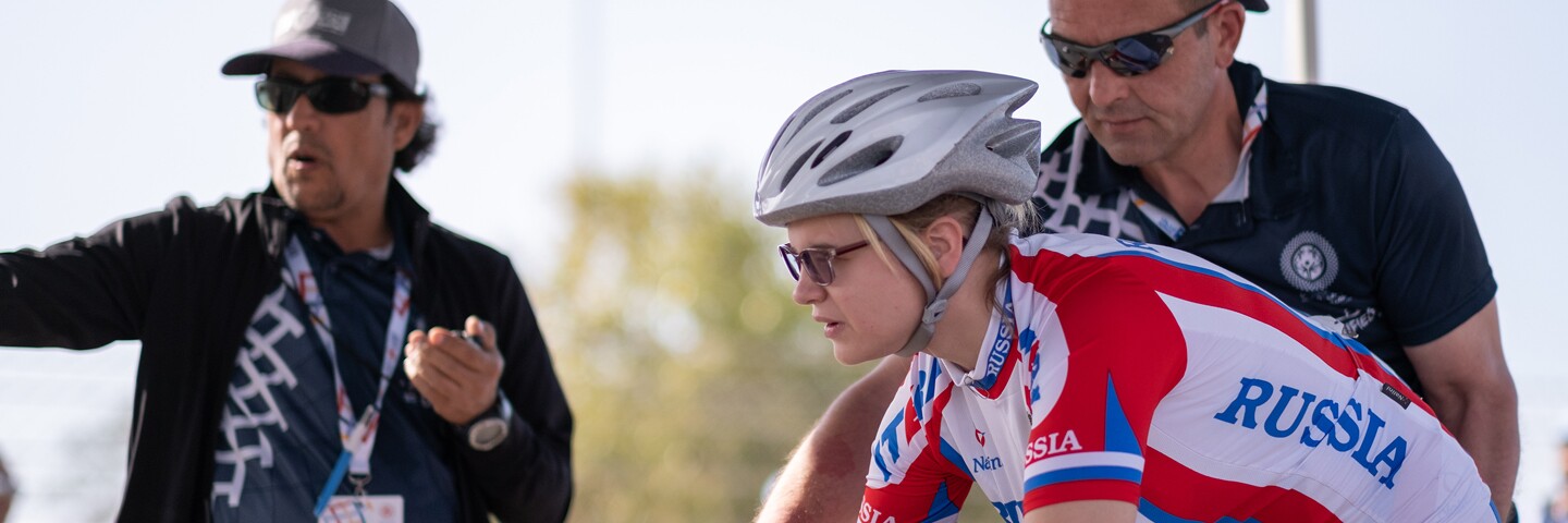 Two delegates assisting an athlete before a cycling performance.