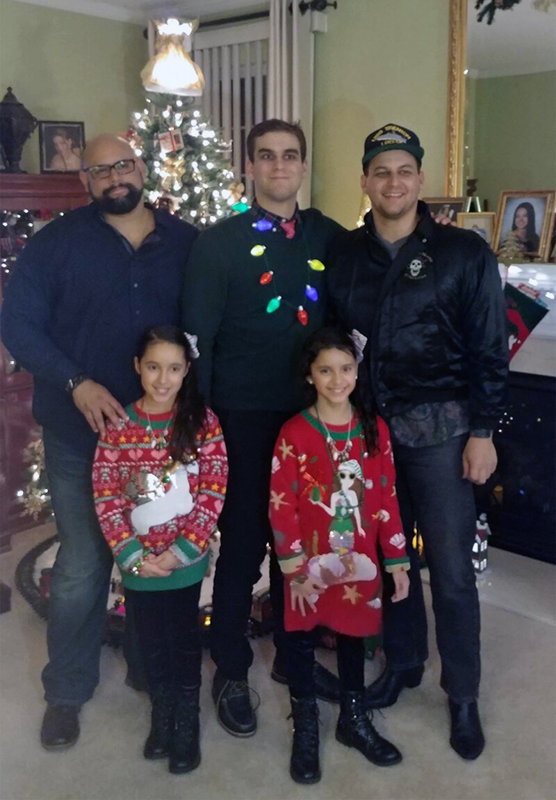 Coach Roberto’s three sons and and two granddaughters standing in front of a Christmas Tree.