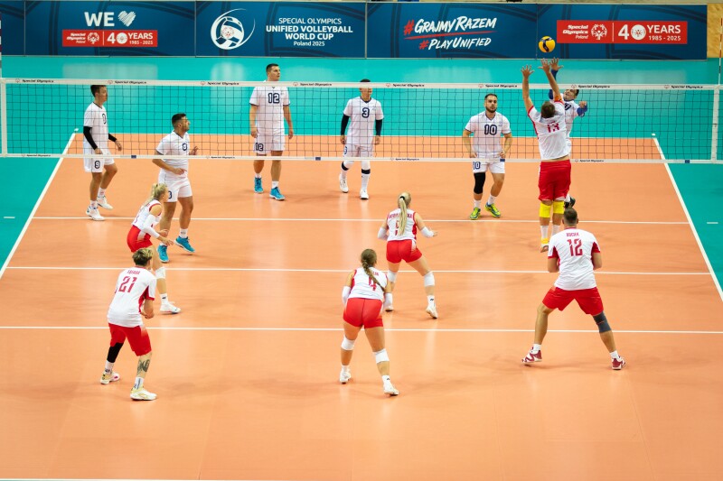 Wide view of the game between Poland and Serbia. Saša spikes a ball and a Polish player attempts to block it