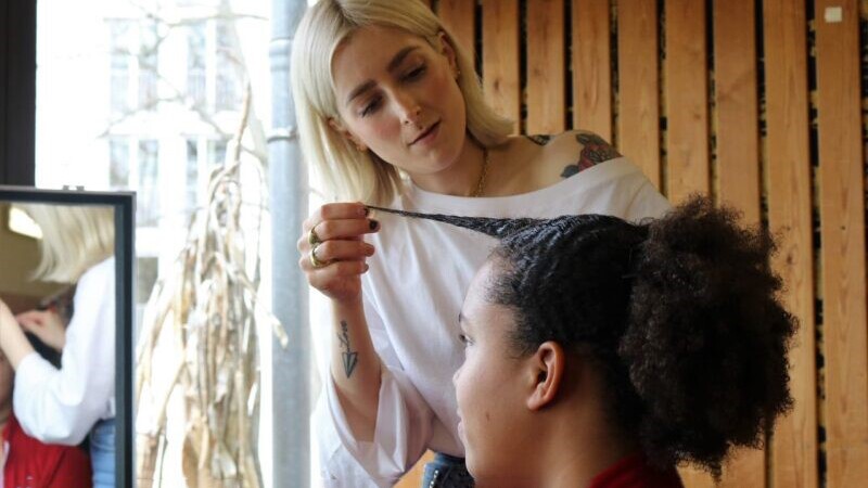 Athlete and model getting her hair done by a stylist.