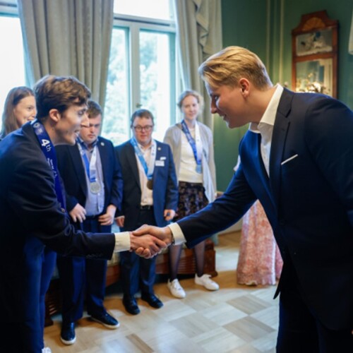 Man shaking athlete's hand in a formal setting. 