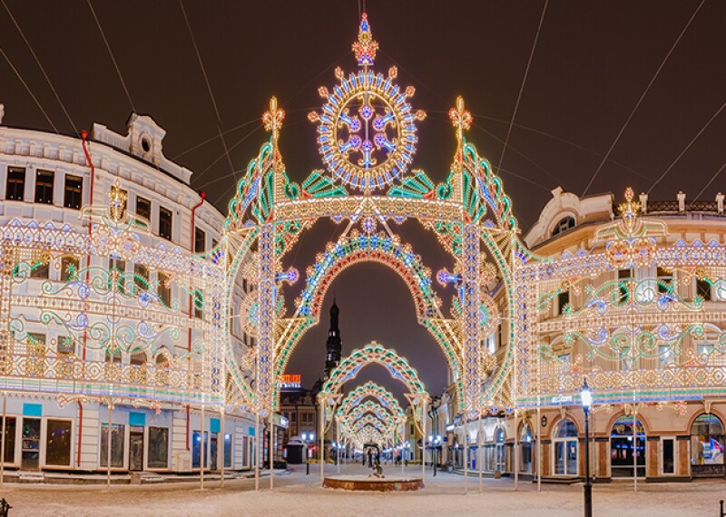 Colorful lights on buildings located on snow covered street.