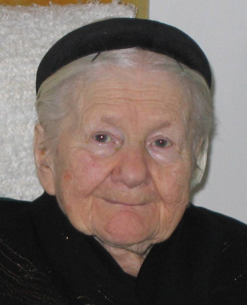 A small elderly woman smiles for the camera.