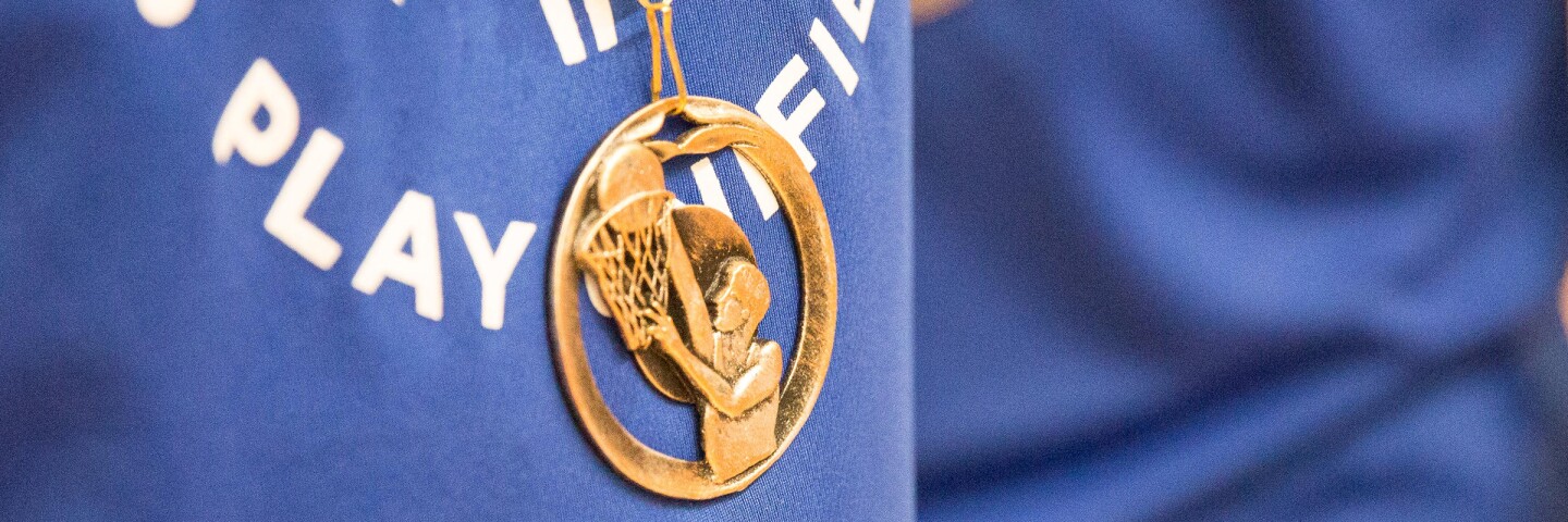 Athlete with a blue Play Unified shirt on and a gold European Basketball medal hanging down.