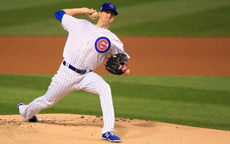 Kyle Hendricks on the pitchers mount wearing his white and blue pin striped Chicago Clubs uniform throwing a pitch.