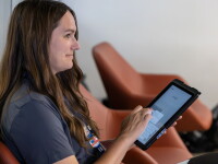 Woman sitting down using an interactive digital pad. 
