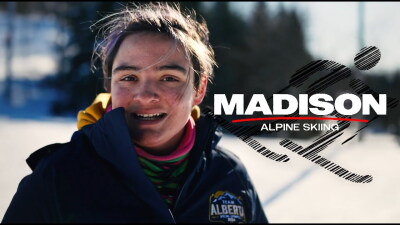 Young woman smiling outside in the snow. text reads: Madison: Alpine Skiing
