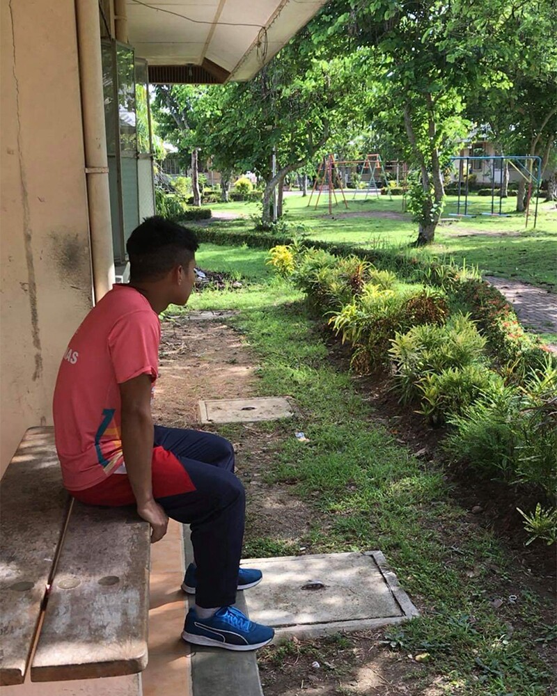 AJ sitting on a bench looking out into a park.