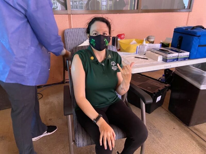 Renee Manfredi sits in a chair at a clinic with her sleeve rolled up to her shoulder right before she gets the vaccine.