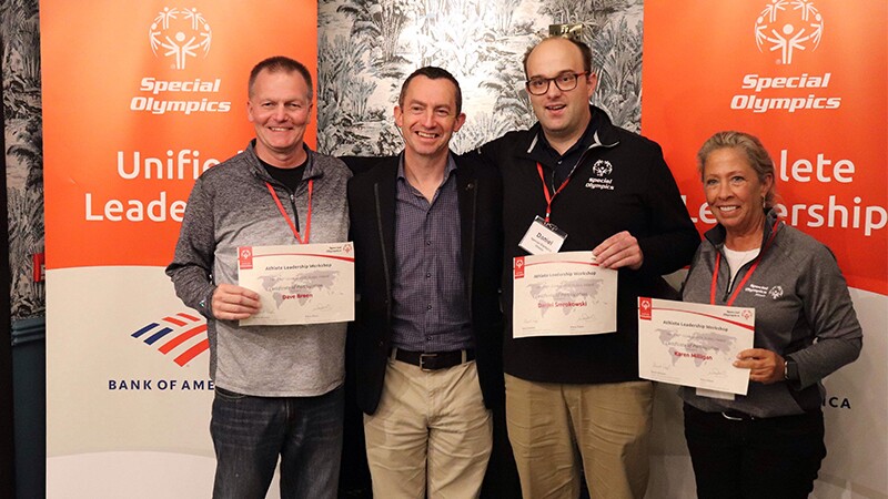 A group of people pose for a photo. They are smiling at the camera and holding certificates.