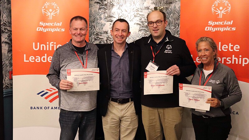 A group of people pose for a photo. They are smiling at the camera and holding certificates. 