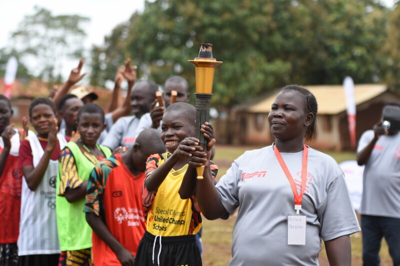 Coach and smiling young athlete proudly hold the torch.