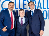 Three men standing side by side in front of Volleyball Federation signage. 