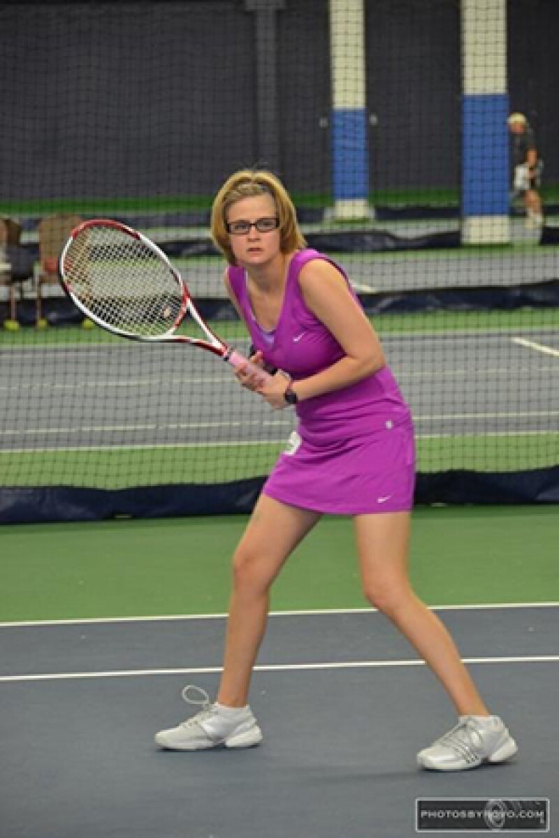 Hillary Kern holding a racket on the court dressed in all purple, waiting for the tennis ball.