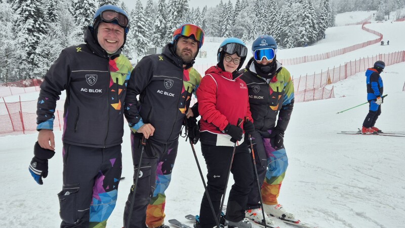 Three skyers with their skis on and on the snow next to another man. 