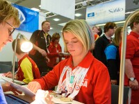 Daina Shilts sitting at a desk with her medals around her neck reading over a card with a health representative.