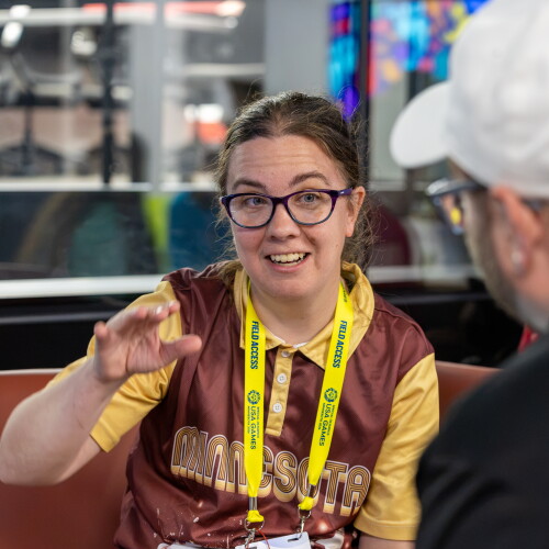 Young woman speaking and gesturing while a person pays attention. 