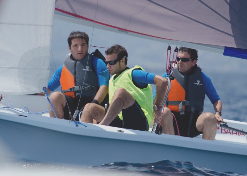 Athlete sailing while his team assists. 