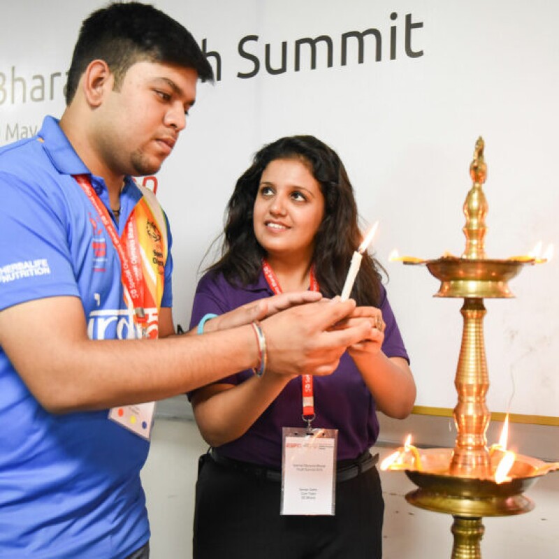 Young man and young woman lighting candles and putting them in a decorative candle holder.