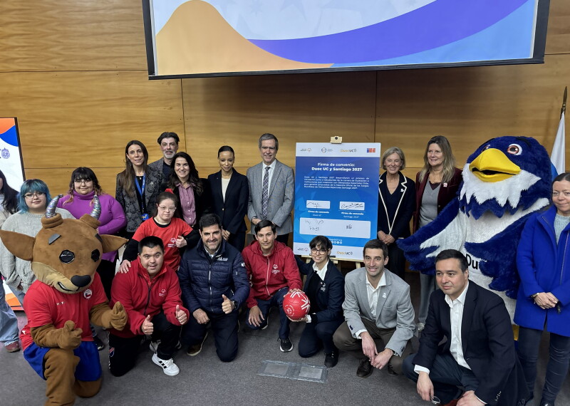 People both kneeling and smiling in a group posing for a photo alongside two mascots (bird and bull)