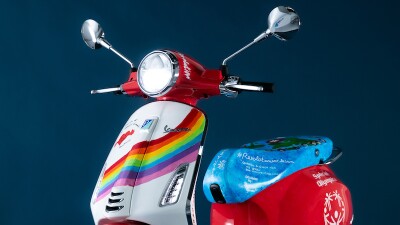 red vespa cycle with blue seat and white front with rainbow design
