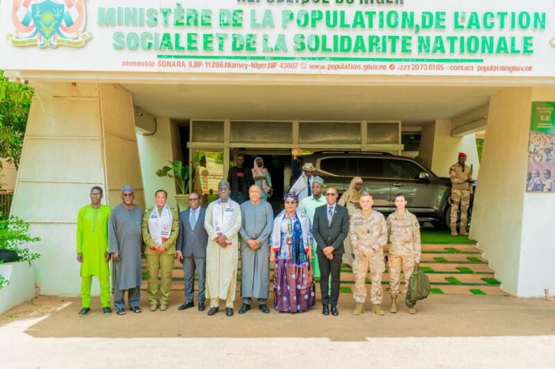 Funcionarios y personal militar se encuentran debajo de un gran cartel frente al Ministerio de Población, Acción Social e Integración Nacional en Niamey, Níger. 