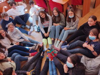 A group of students sitting in a circle with their feet together and showing off their socks. 