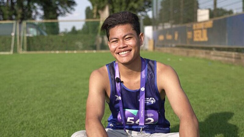 Young man sitting in a field on the grass. 