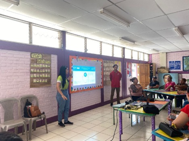 Docente facilitando una sesión formativa inclusiva en el aula, utilizando una pantalla digital, mientras un grupo diverso de participantes escucha y comparte. El entorno refleja el enfoque de Olimpiadas Especiales, promoviendo la inclusión, el aprendizaje conjunto y la participación de personas con discapacidad intelectual en contextos educativos.
