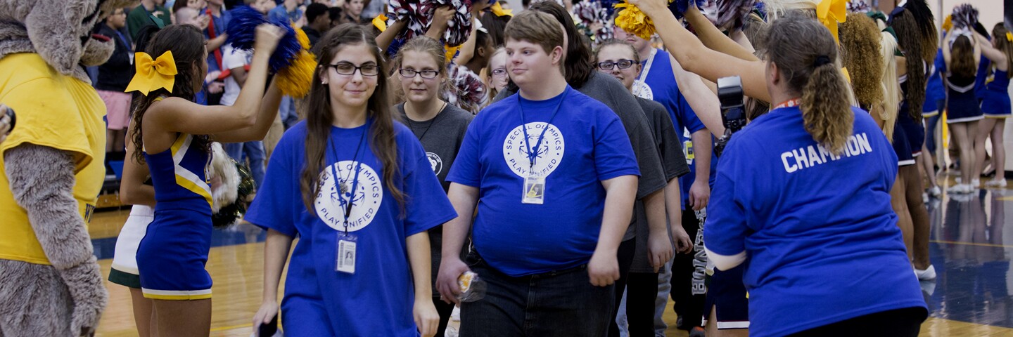 Students, and staff in a gymnasium with cheerleaders.