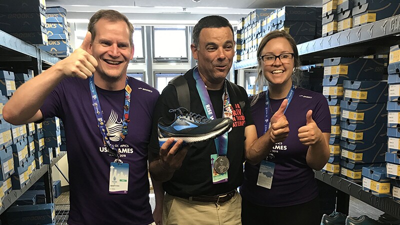 Finish Line employees and Special Olympics athlete give a thumbs up at the Finish Line and Brooks Running shoe giveaway at 2018 Special Olympics USA Games.