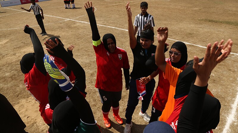 Female players stand in circle with hands in air.