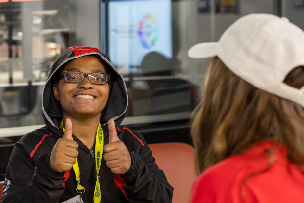 Young woman in a hoodie giving a double thumbs up. 