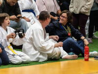 A woman and man look at each other at the sidelines of a judo match. 