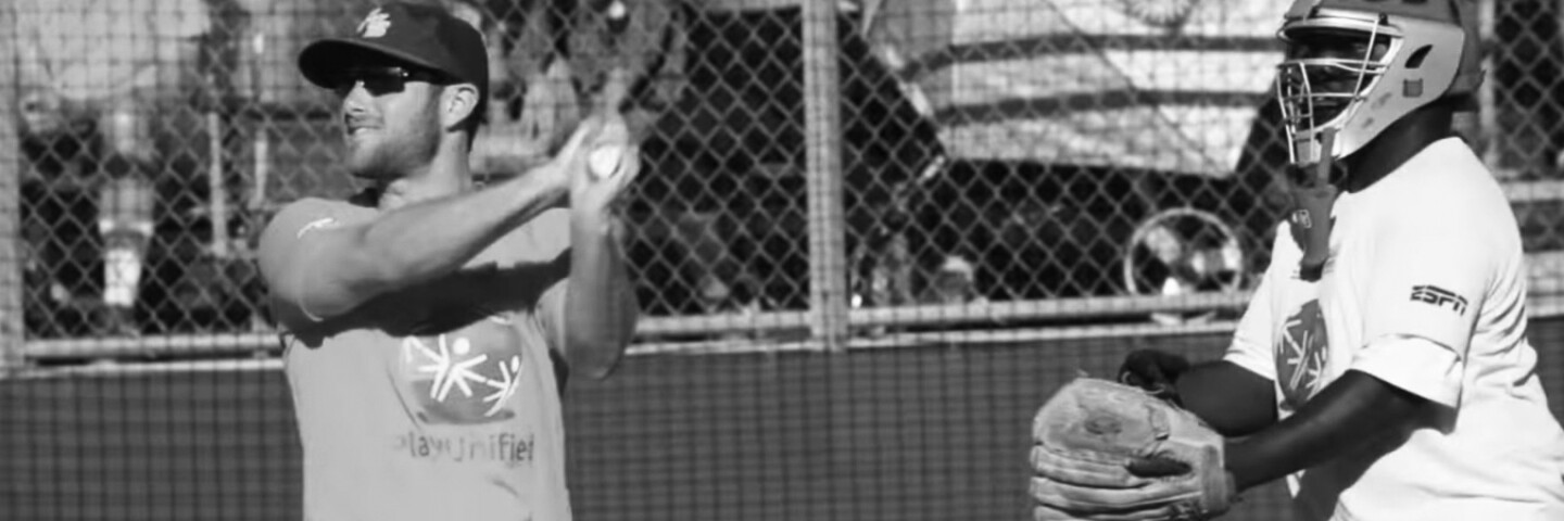 man in a play unified t-shirt hitting a ball as the catcher prepares to catch it.