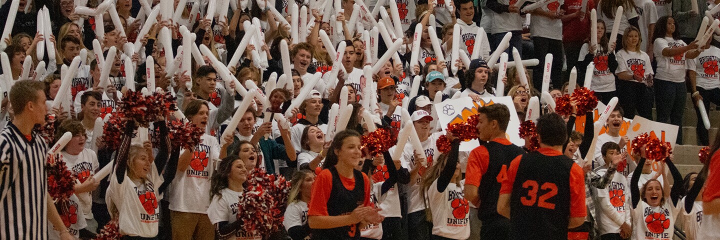 A large group of students cheering in a gymnasium.