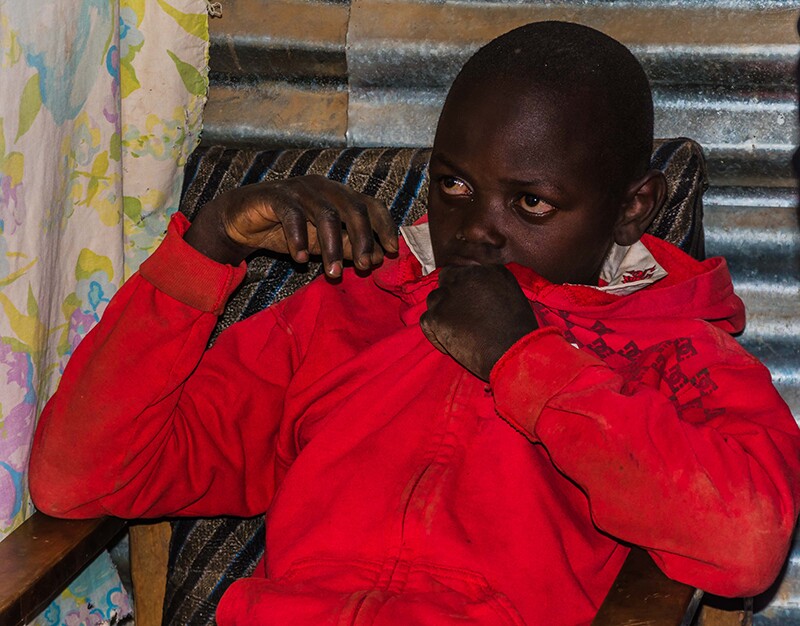 Zadock Mavinda, a 16-year old, sits in his house during the Golisano Foundation's visit.