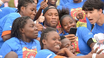 Didier Drogba surrounded by athletes for a group photo. 
