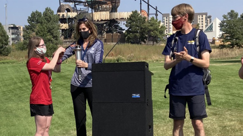 Three people stand on a stage behind a podium.