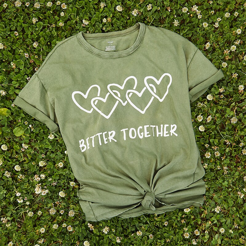 Aerie "Better Together" green t-shirt on a bed of dandelions.