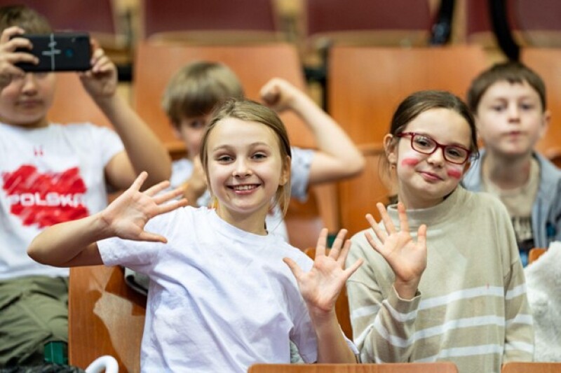 Children sit in the stands as they cheer on Poland