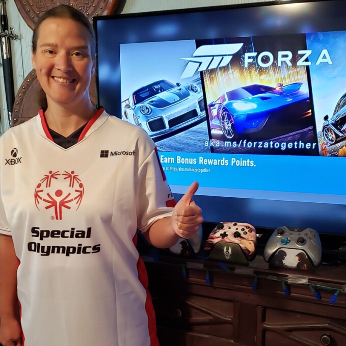 800x800 - Amber Gertsch giving a thumbs up in front of a television screen featuring the game Forza.