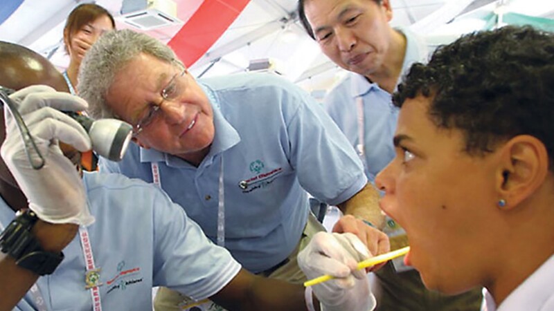 Dr. Perlman observing a tech performing an exam on an athlete as an observers watches the process.