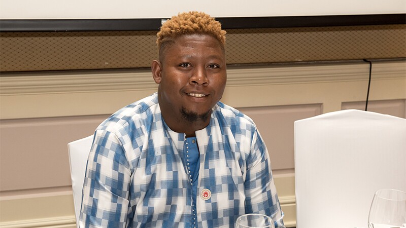 Jimmy Masina sits and looks at a camera. He is wearing an Abu Dhabi 2019 World Games pin.