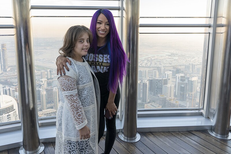 WWE Superstar Sasha Banks and Team UAE athlete Chaica Sultan Al Qasimi pose at the Burj Khalifa. In the background is the city of Abu Dhabi.