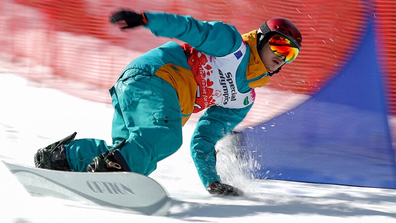 Snowboarder in a turquoise ski suite going down on the slops.